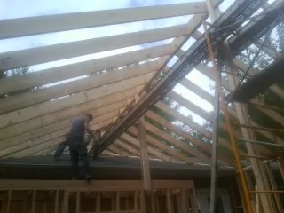 Rafters going up over a new addition with a worker on the wall in Missouri City