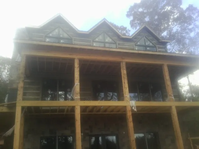 Dormers and porch framing on a large log home under construction — Roof Coating work by our crew in Missouri City