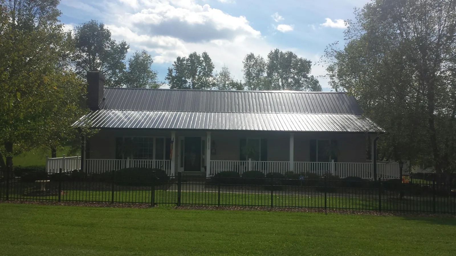 Gray metal roof on a brick ranch with a full width front porch — Gutter Guard Installation work by our crew in Missouri City