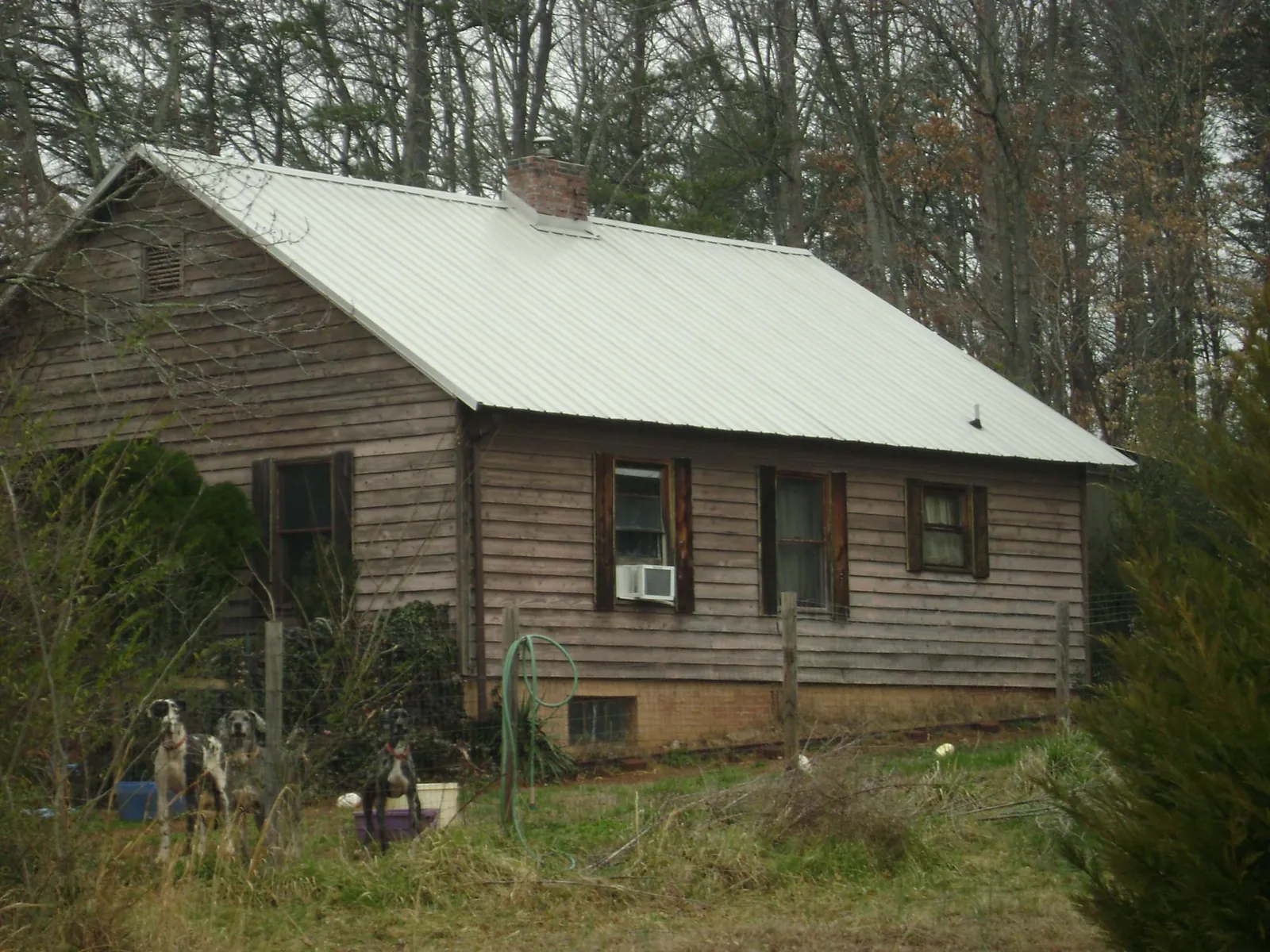 White metal roof on an old wood sided farmhouse, from a Metal Roof Installation job in Missouri City